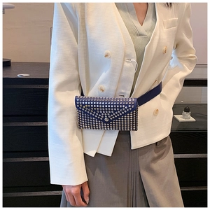 Blue leather belt bag with silver rivets shown on a waist belt over a white suit jacket