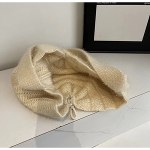 Détail du bonnet en maille crème avec texture duveteuse et cordon de serrage réglable