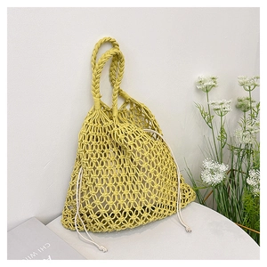 Close-up of bright yellow crochet knit tote with beige drawstring inner bag and dual handles