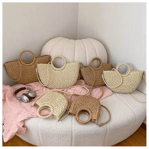 Détail de sacs en paille tressée kaki et beige posés sur un canapé texturé doux