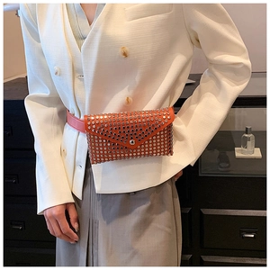 Detail of trendy orange leather waist bag with silver studs on white blazer