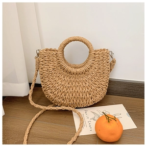Détail du sac en paille tressée avec poignée ronde et bandoulière amovible