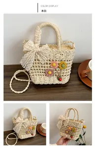 Dettaglio borsa in paglia intrecciata bianco panna con fiocco in pizzo e decori floreali