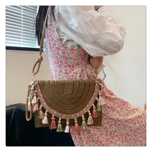 Detail of bohemian woven bag featuring dark coffee straw texture and colorful tassels