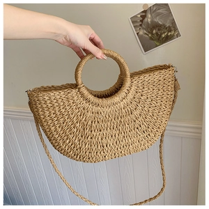 Détail du sac demi-lune en paille tissée avec poignée ronde et bandoulière amovible