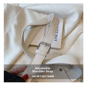 Detail of adjustable cream leather strap with silver metal buckle on a small waist bag