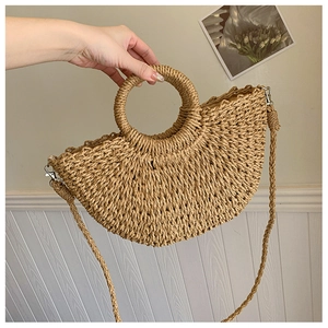 Détail d'un sac demi-lune en paille tressée avec poignée ronde et attaches en métal argenté