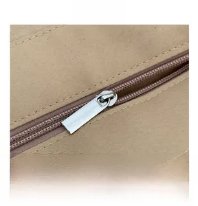 Close-up of smooth silver metal zipper and hardware on beige woven canvas bag