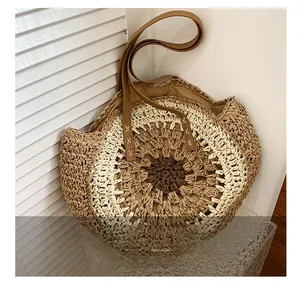 Close-up of woven straw tote bag with brown leather straps and detailed stitching
