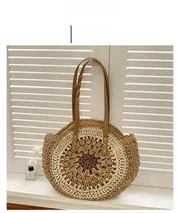 Close-up of woven straw handbag with brown leather handles on a bright sunlit background