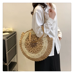 Close-up of bohemian round straw bag with multi-tone woven pattern and leather straps