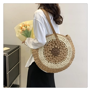 Detailed texture of hand-woven straw tote with leather shoulder strap and stitching