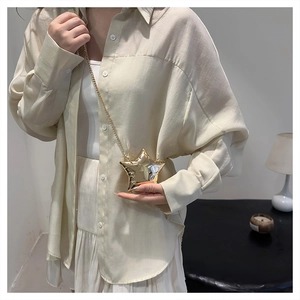 Détail d'un mini sac de soirée doré en forme d'étoile avec une fine bandoulière chaîne