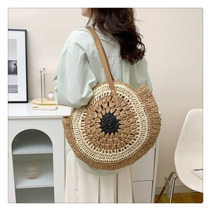 Detail of bohemian round straw bag featuring woven concentric patterns and leather strap