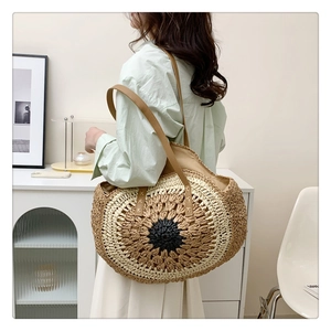 Detail view of woven straw tote bag featuring radial pattern and brown leather straps