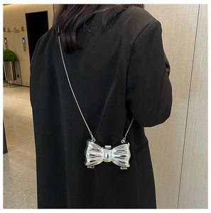 Detail shot of a silver mirror acrylic bow-shaped clutch with a metallic chain strap
