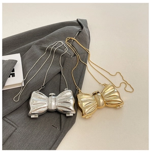 Detailed view of bow-shaped metallic mini clutch bags in polished gold and silver finishes