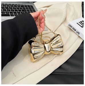 Close-up of golden bow-shaped evening clutch with mirror metallic finish and chain strap