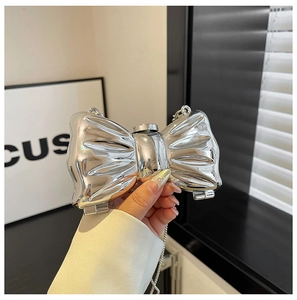 Close-up of a silver bow-shaped mini acrylic clutch bag with a glossy mirror finish and chain