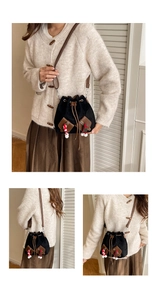 Détail du sac seau vintage avec cordon, finitions en cuir et breloques de fête
