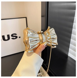 Macro detail of bow-shaped mirror acrylic clutch bag with golden chain and gradient finish