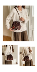Détail du sac seau vintage en daim marron avec des breloques festives en pompons doux