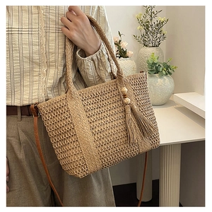 Detail van de stro geweven tas met mesh-patroon en stijlvolle decoratieve kwastjes