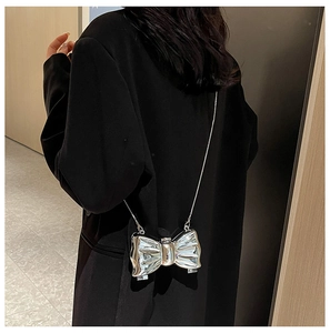 Detail of silver metallic bow evening bag with mirror finish and stylish chain strap