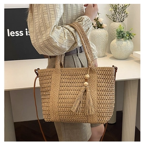 Detail van handgemaakte strooien tote bag met houten kralenkwastje en leren riem