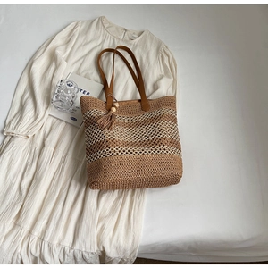 Détail du sac cabas en paille avec anses en cuir marron et pompons en perles de bois