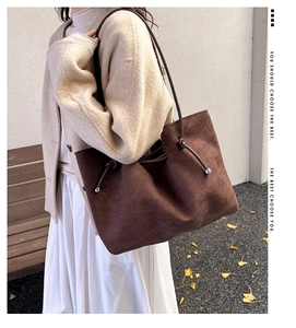 Detail of brown suede tote bag with side drawstrings and metallic bead accents