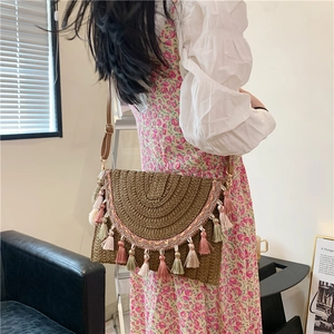 Bohemian straw envelope bag with colorful tassels and a brown leather shoulder strap