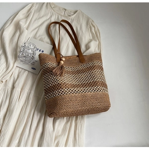 Détail du sac cabas tissé à carreaux avec brides en cuir et pompon décoratif