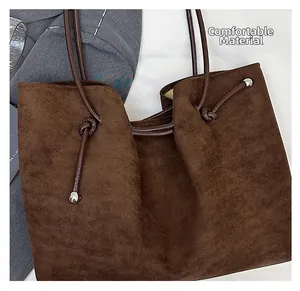 Detail of premium brown suede tote bag with slim shoulder strap and silver metal sphere
