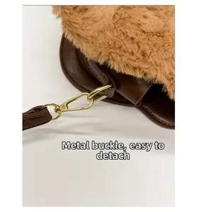 Detail of detachable golden metal lobster clasp on brown plush faux fur crossbody bag