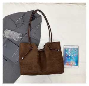 Detail view of large dark brown suede tote bag showing slim straps and drawstring knot