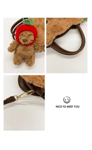 Detail view of plush bear bag featuring strawberry hat and sturdy metal strap hooks