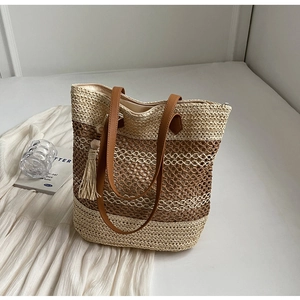 Détail du cabas rayé en paille avec lanières en cuir marron et pendentif pompon
