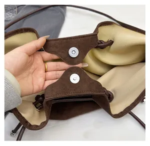 Detail of metal magnetic closure on brown suede shoulder bag with inner lining