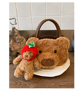 Detail of cute plush bear handbag with leather handle and strawberry bear charm