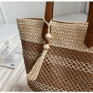 Détail du cabas en paille tressée bicolore avec texture ajourée et pendentif à pompon chic