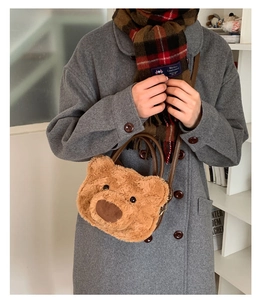 Detail of plush bear-shaped handbag with leather handles worn over a winter wool coat