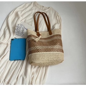 Vue détaillée du sac cabas en paille à carreaux avec anses en cuir et pompon en perles