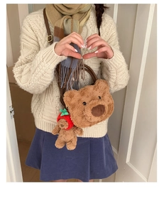 Detail view of plush bear crossbody bag with a cute strawberry hat bear charm accessory