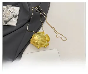 Dettaglio della mini borsa da sera dorata a forma di pesce con squame e tracolla