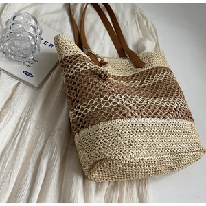 Détail du sac cabas en paille tissé avec rayures, brides en cuir et pompon perlé
