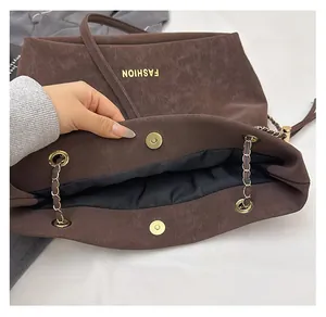 Macro shot of the dark brown leather tote bag with a golden magnetic clasp and fashion logo