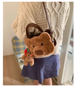 Detail of plush bear shoulder bag with strawberry bear charm and brown leather straps