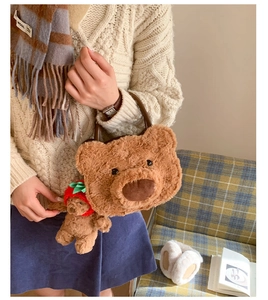 Detail of soft brown plush bear handbag with a cute strawberry hat bear charm accessory