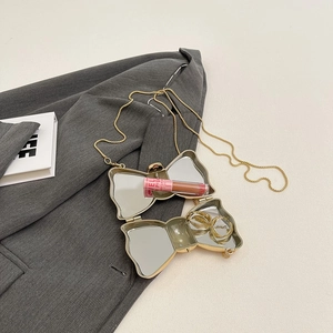 Golden bow-shaped acrylic evening clutch with built-in mirrors and fine chain strap